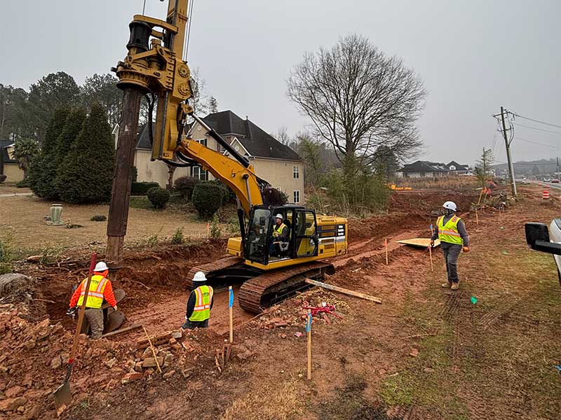 Construction crew operating pile driving equipment.